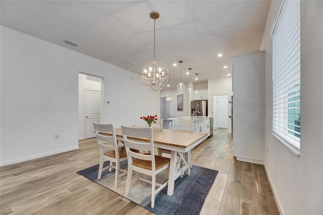 dining space featuring a chandelier, light wood-type flooring, visible vents, and baseboards