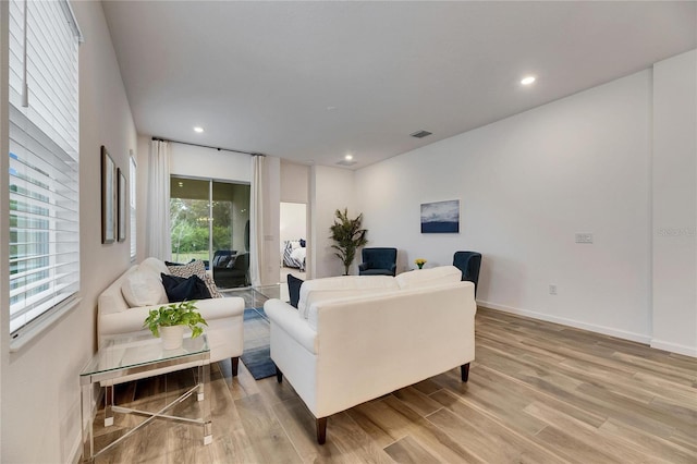 living room featuring recessed lighting, baseboards, visible vents, and light wood finished floors