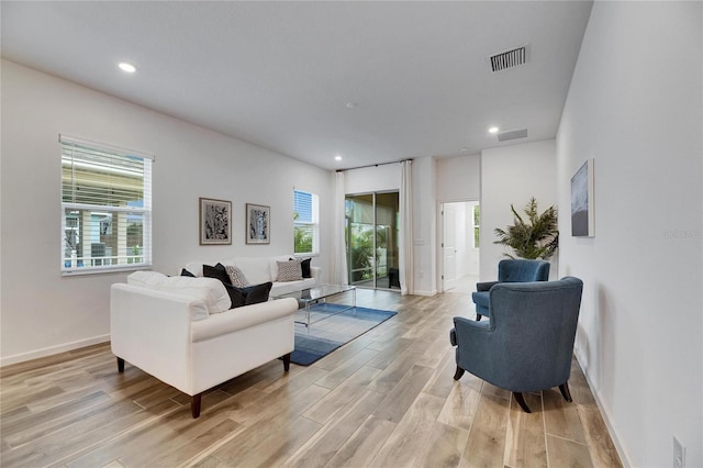 living room with light wood-type flooring, visible vents, baseboards, and recessed lighting