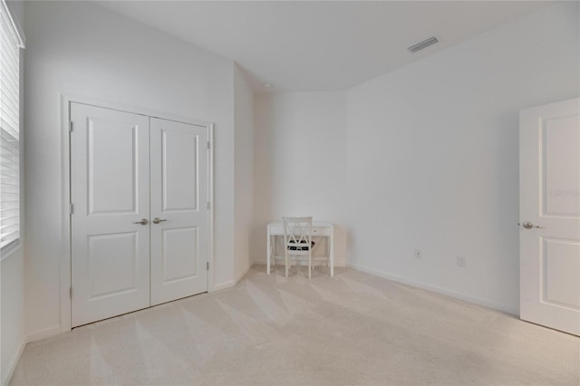 unfurnished bedroom featuring baseboards, visible vents, a closet, and light colored carpet