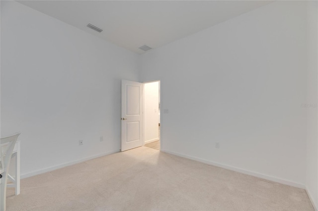 unfurnished room with visible vents, baseboards, and light colored carpet