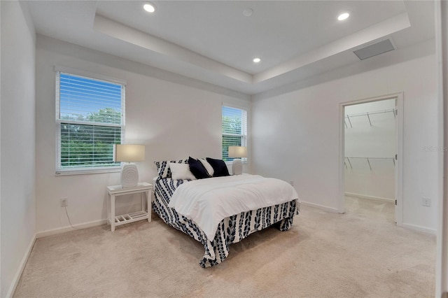 carpeted bedroom featuring a tray ceiling, recessed lighting, visible vents, a spacious closet, and baseboards