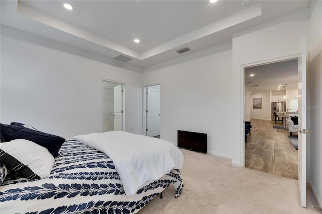 bedroom with recessed lighting, a raised ceiling, visible vents, light carpet, and baseboards