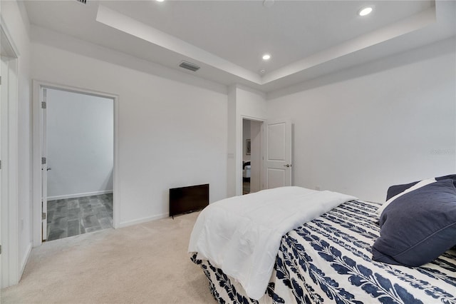 bedroom with recessed lighting, light carpet, visible vents, baseboards, and a raised ceiling