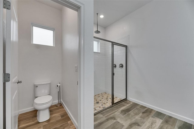 full bath featuring baseboards, a shower stall, toilet, and wood finished floors