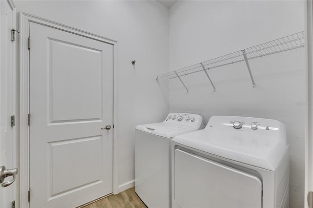 clothes washing area with laundry area, light wood finished floors, and washer and clothes dryer