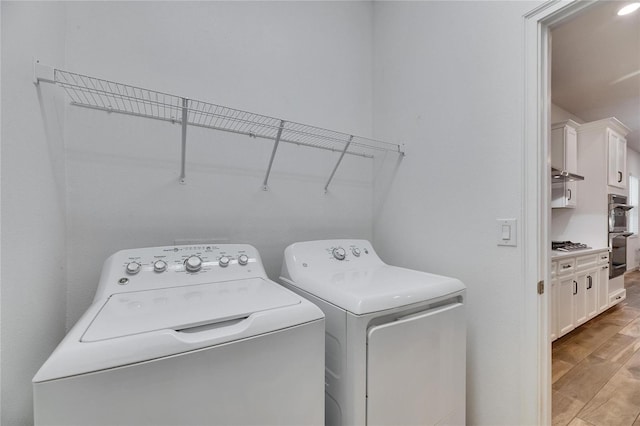 laundry area with washing machine and dryer, laundry area, and light wood-style flooring