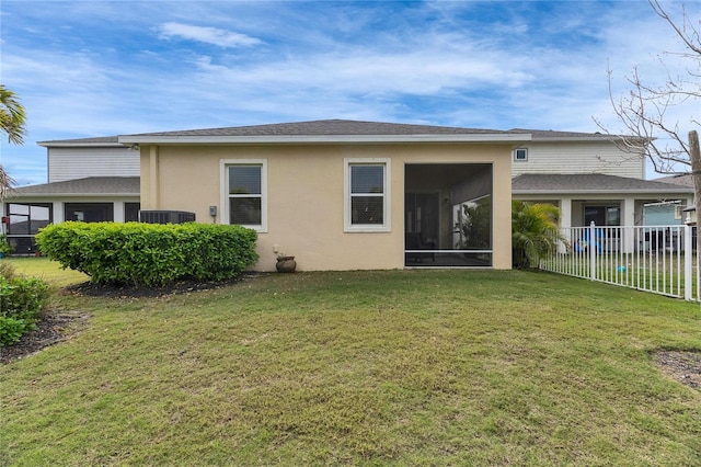 rear view of property featuring a sunroom, fence, stucco siding, and a yard