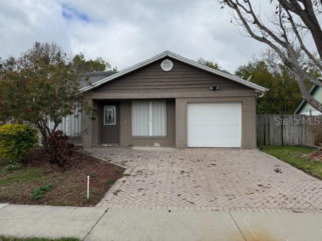 ranch-style house featuring decorative driveway, fence, and an attached garage