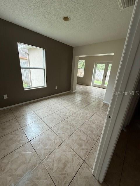 unfurnished room featuring a textured ceiling, visible vents, and baseboards