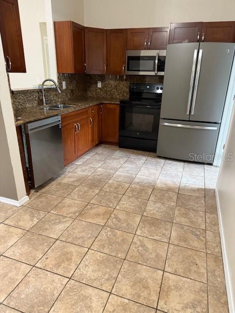 kitchen with tasteful backsplash, appliances with stainless steel finishes, light tile patterned flooring, a sink, and baseboards