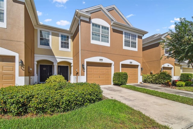 multi unit property with driveway, an attached garage, and stucco siding