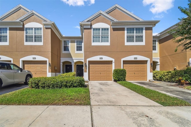 multi unit property with driveway, an attached garage, and stucco siding