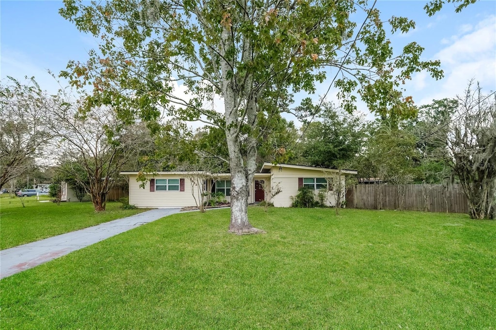 single story home with driveway, fence, and a front yard