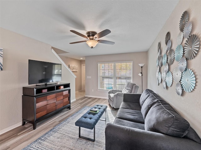 living room featuring light wood finished floors, a ceiling fan, and baseboards