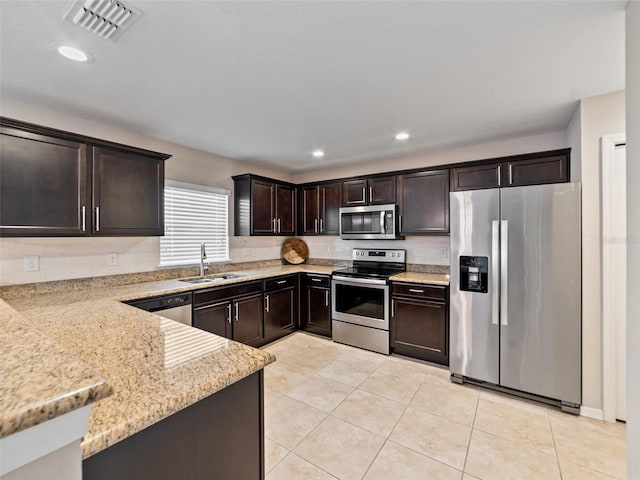 kitchen featuring light tile patterned flooring, dark brown cabinetry, stainless steel appliances, a sink, and visible vents