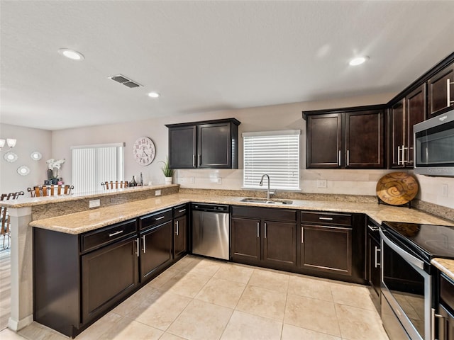 kitchen with stainless steel appliances, visible vents, a sink, dark brown cabinets, and a peninsula