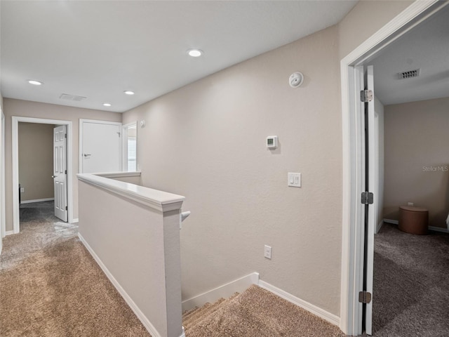 hall featuring visible vents, carpet floors, an upstairs landing, and baseboards