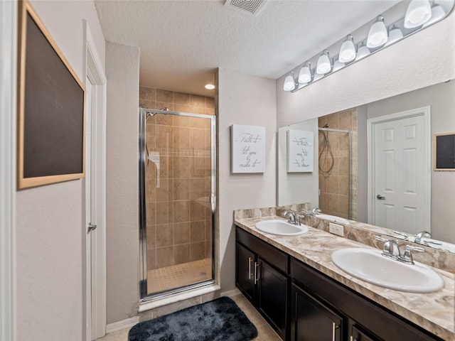 full bathroom with double vanity, a stall shower, visible vents, and a sink