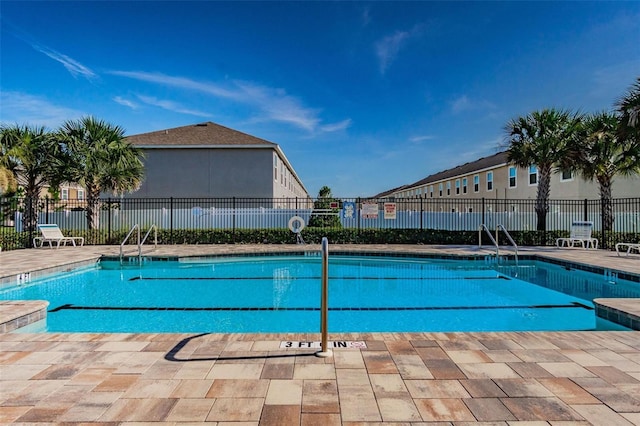 pool with a patio area and fence