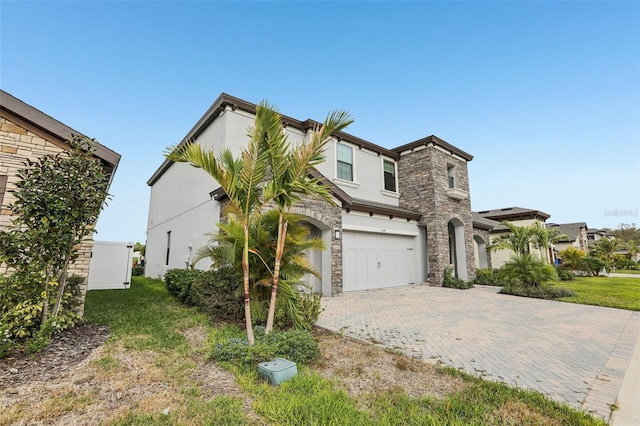 view of front of property with stone siding, decorative driveway, a garage, and stucco siding