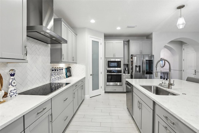 13176 Twin Bridges Dr, Riverview, FL 33579 - kitchen with wall chimney range hood, stainless steel appliances, a sink, arched walkways, and gray cabinets