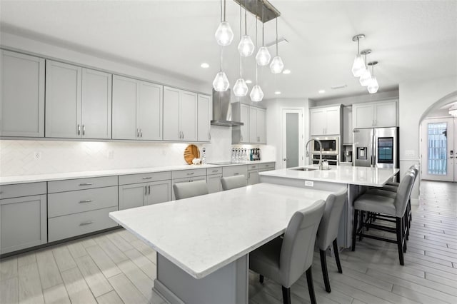 13176 Twin Bridges Dr, Riverview, FL 33579 - kitchen featuring stainless steel appliances, wall chimney range hood, gray cabinets, arched walkways, and a spacious island