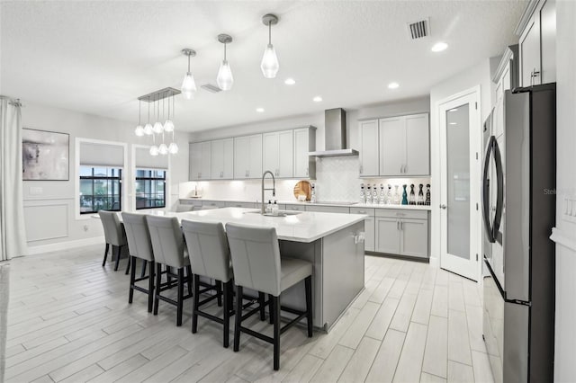 13176 Twin Bridges Dr, Riverview, FL 33579 - kitchen with freestanding refrigerator, wall chimney exhaust hood, tasteful backsplash, light countertops, and light wood finished floors