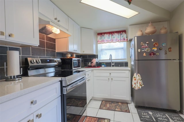 kitchen featuring under cabinet range hood, a sink, white cabinetry, appliances with stainless steel finishes, and backsplash