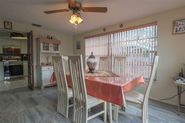 dining space featuring a healthy amount of sunlight, visible vents, ceiling fan, and a textured ceiling