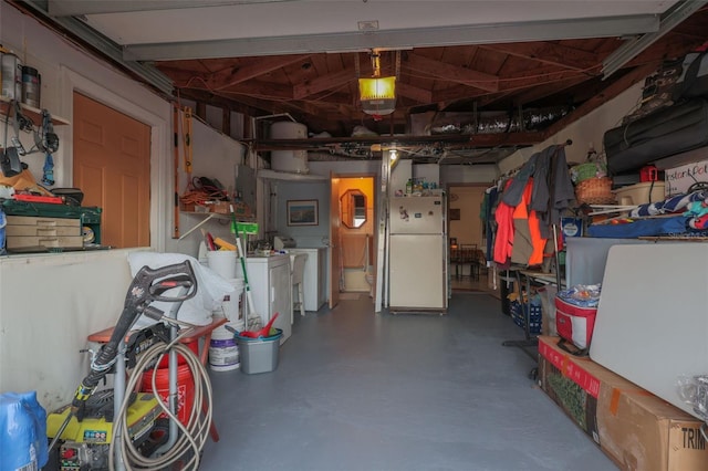 garage with a garage door opener, washing machine and clothes dryer, and freestanding refrigerator