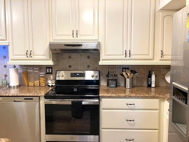 kitchen featuring tasteful backsplash, light stone countertops, stainless steel appliances, under cabinet range hood, and white cabinetry