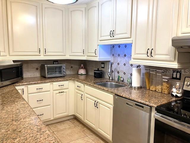 kitchen with stainless steel appliances, tasteful backsplash, a sink, and a toaster