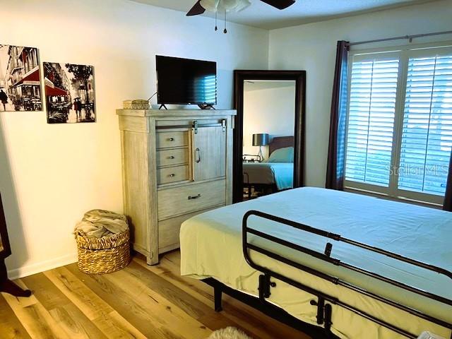 bedroom featuring baseboards, light wood-style flooring, and a ceiling fan