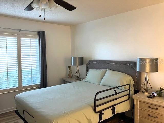 bedroom featuring dark wood-style floors, ceiling fan, and a textured ceiling