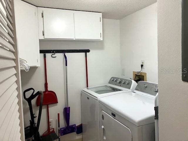 washroom with a textured ceiling, separate washer and dryer, and cabinet space