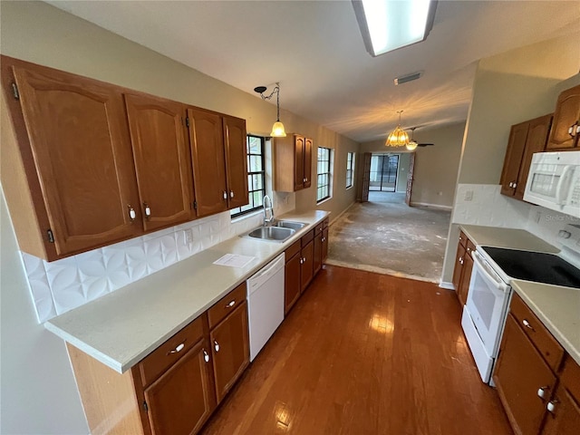 kitchen featuring vaulted ceiling, white appliances, brown cabinets, and a sink