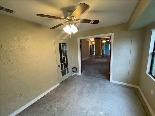 spare room featuring baseboards, visible vents, and a textured wall