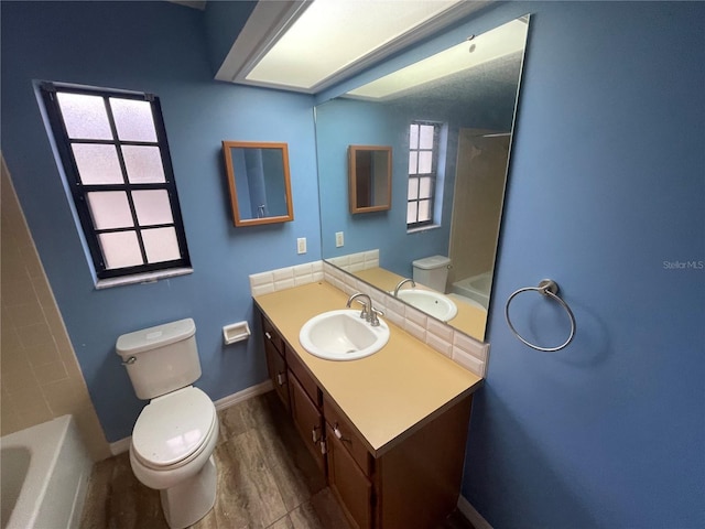 bathroom with tub / shower combination, vanity, toilet, and baseboards