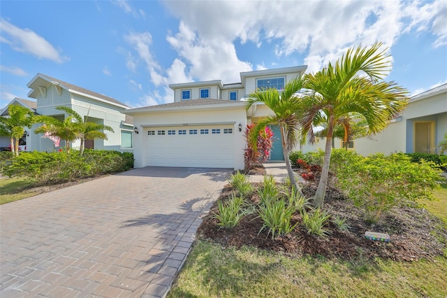 view of front of home with decorative driveway, an attached garage, and stucco siding