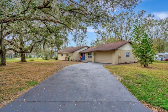 single story home featuring a garage, driveway, and a front lawn