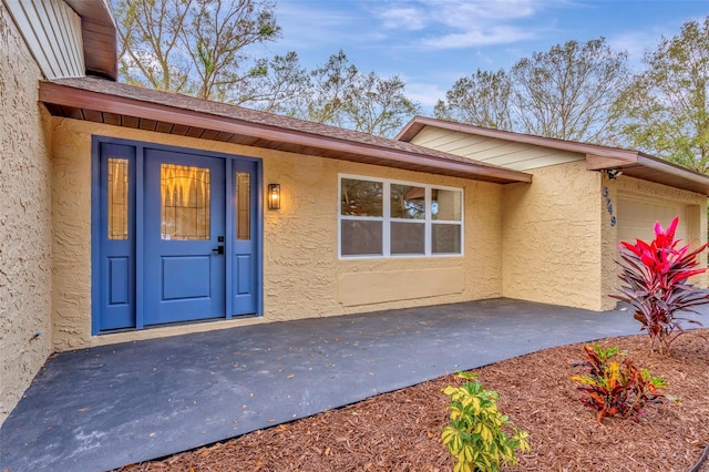 doorway to property featuring a garage and stucco siding