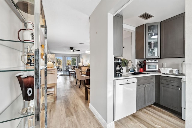 bar with light wood finished floors, visible vents, a sink, white appliances, and baseboards