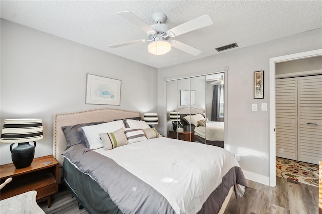 bedroom featuring baseboards, visible vents, ceiling fan, wood finished floors, and a textured ceiling