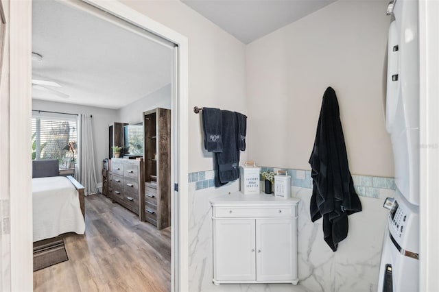 bathroom featuring ensuite bathroom, a wainscoted wall, wood finished floors, and tile walls