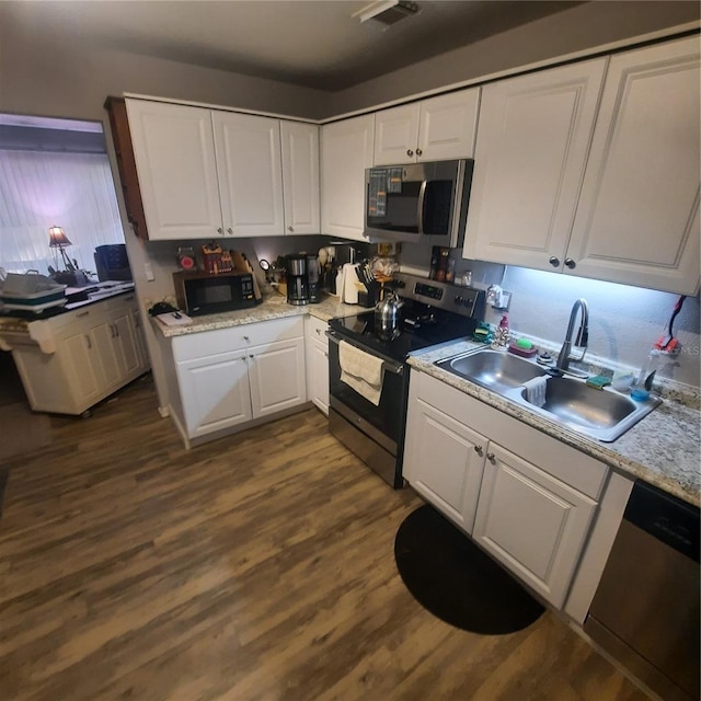 kitchen featuring white cabinets, appliances with stainless steel finishes, dark wood-type flooring, and a sink