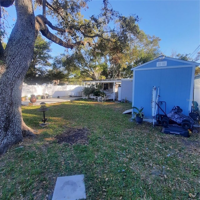 view of yard with a storage unit, an outbuilding, and fence