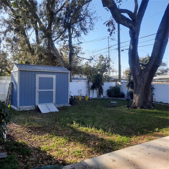 view of yard with a fenced backyard, a storage unit, and an outdoor structure