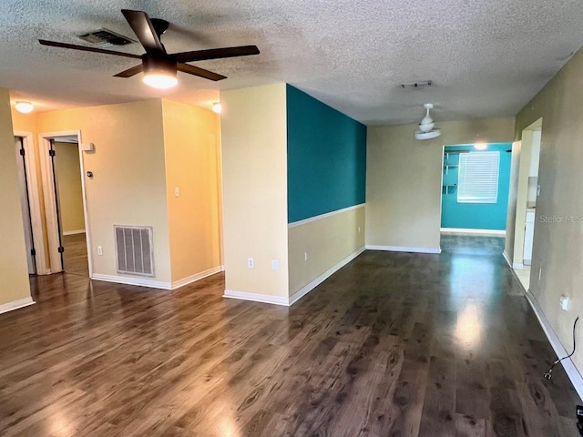 unfurnished room featuring dark wood-type flooring, visible vents, and baseboards