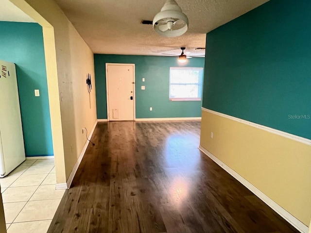 interior space featuring ceiling fan, a textured ceiling, baseboards, and wood finished floors